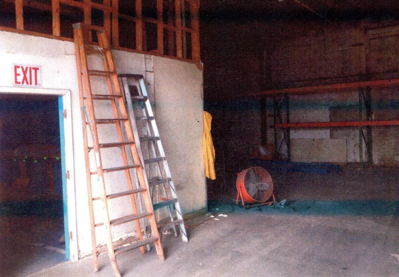 Warehouse interior before renovation with ladders and exposed framing