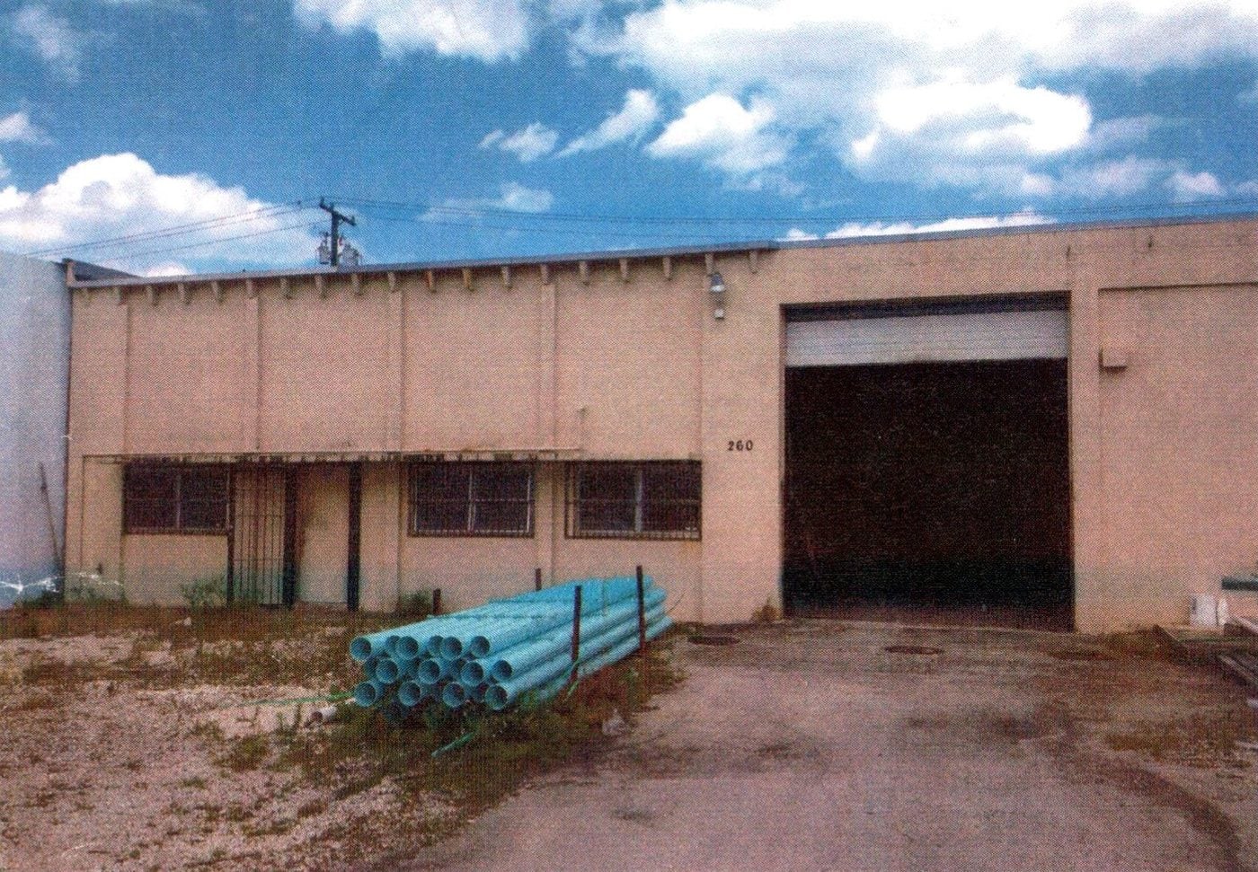 260 SW 21st Terrace before renovation: plain beige warehouse with barred windows