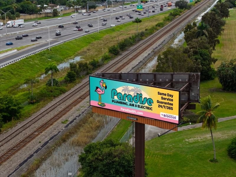 Paradise Plumbing, Air & Electric billboard beside a South Florida highway advertising a same day service guarantee