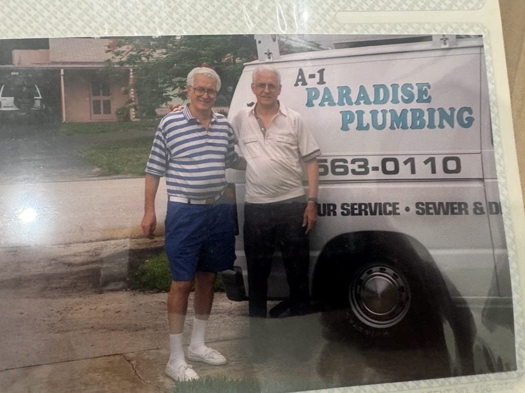Two men standing beside an A-1 Paradise Plumbing van