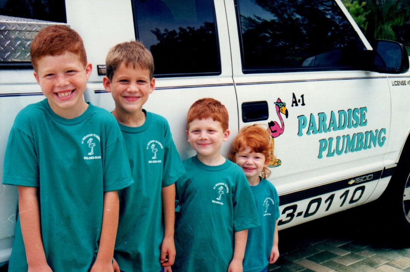The four Rich children in teal Paradise shirts in front of an A-1 Paradise Plumbing truck